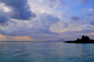 Soft, cloudy evening skies above a calm blue lagoon create a peaceful scene.