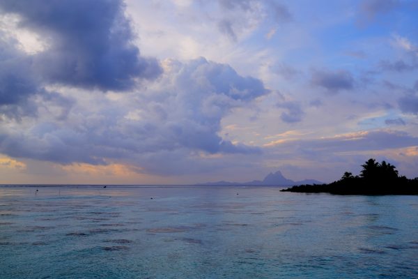 Soft, cloudy evening skies above a calm blue lagoon create a peaceful scene.